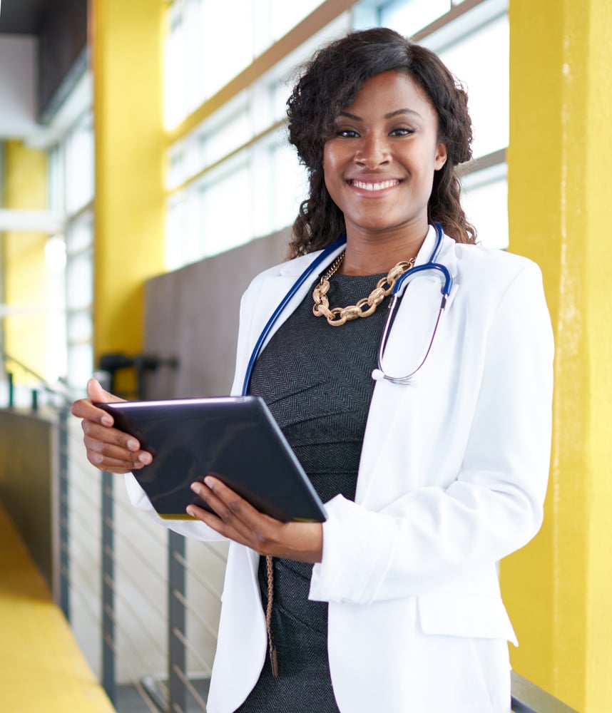 Portrait of a female doctor holding her patient chart on digital tablet in bright modern hospital